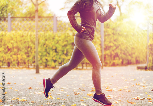 close up of young woman running in autumn park