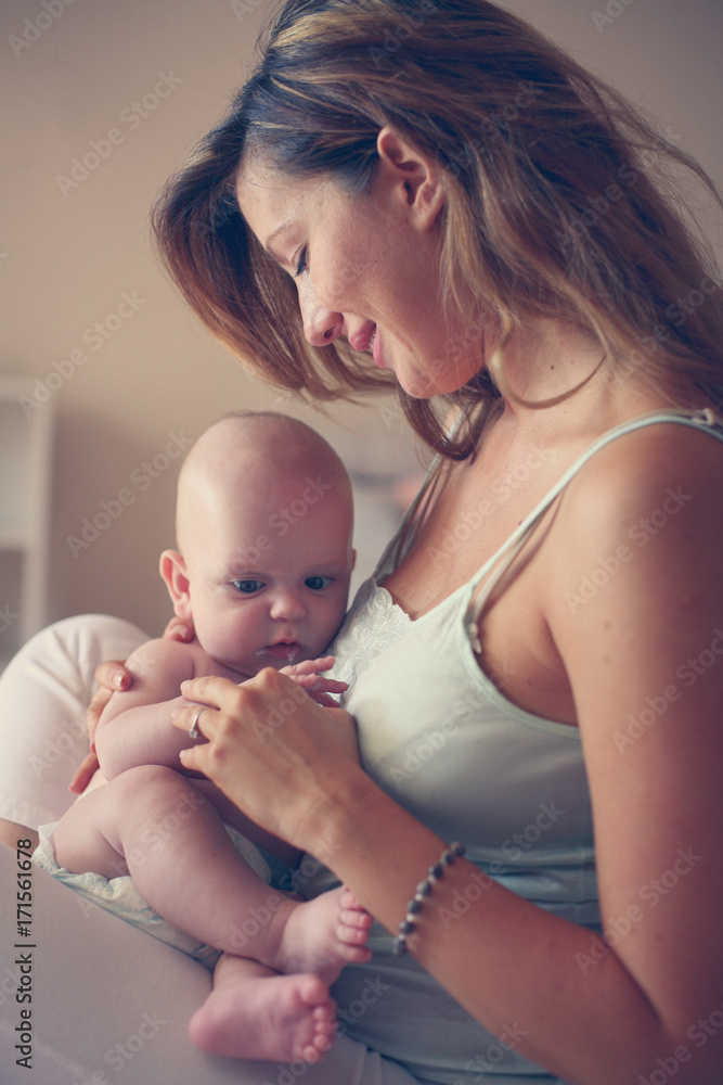 Young mother playing with her baby boy in bed. Mother enjoying in free time with her little cute baby. Young mother playing with her baby boy in bed. Mother enjoying in free time with her little cute baby.