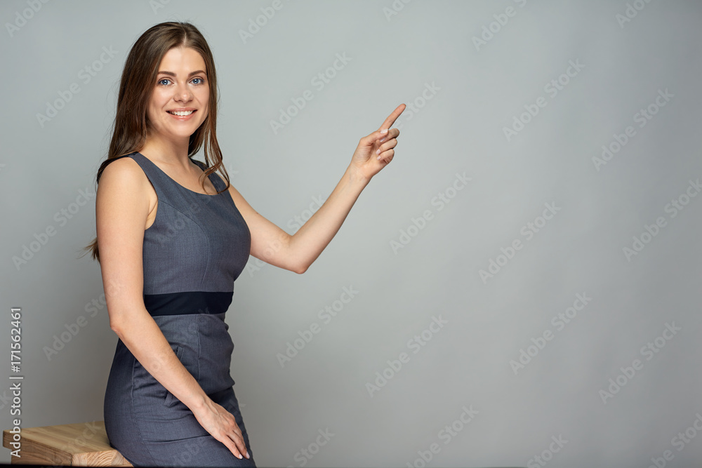 Smiling business woman pointing finger at gray Smiling business woman pointing finger at gray