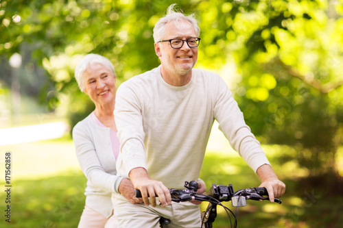 happy senior couple riding bicycle at park