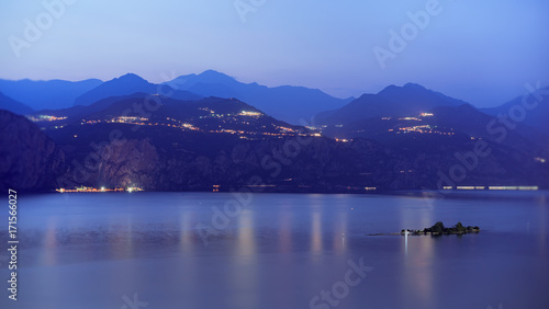 Gardasee am Abend, die kleinen Insel Trimellone und Bergen im Hintergrund. 