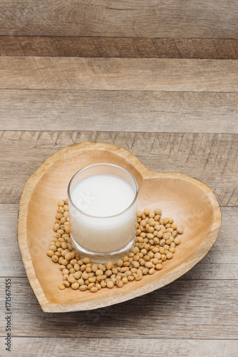 Glass with soy milk and soy bean on wooden heart shape plate