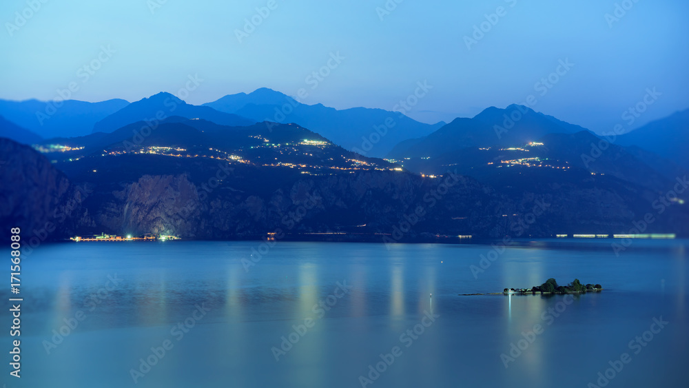 Gardasee am Abend, die kleinen Insel Trimellone  und Bergen im Hintergrund. 
