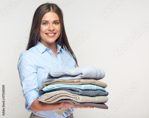 Smiling woman holding stack of warm winter clothes. photo