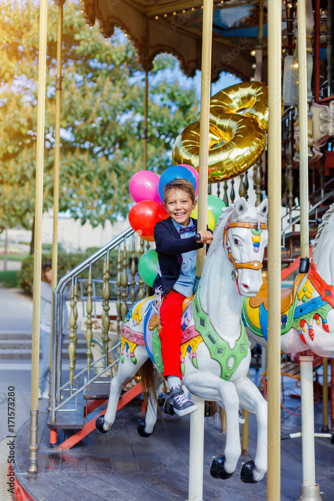 Boy with bunch of colorful balloons on the carousel in Paris.