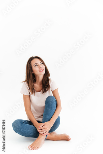 Vertical image of happy brunette woman sitting on the floor