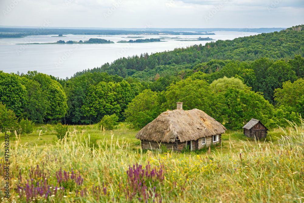 Old house among hills and fields in the background of a huge river Old house among hills and fields in the background of a huge river