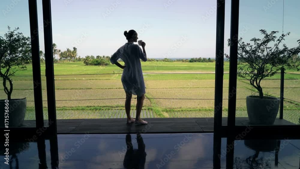 Silhouette of woman walking out on terrace, drinking coffee and admire view
Silhouette of woman walking out on terrace, drinking coffee and admire view