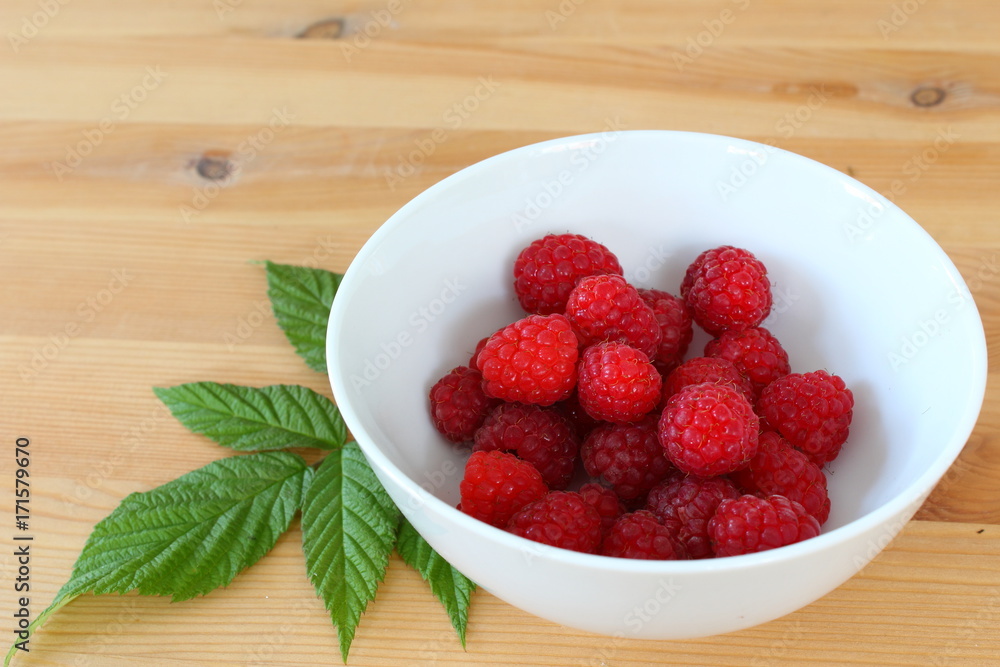 fresh red raspberry fruits in a small white bowl fresh red raspberry fruits in a small white bowl