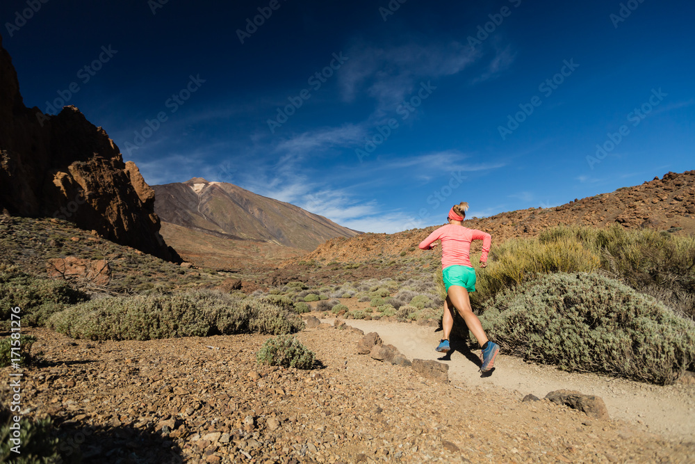 Trail running woman in mountains on sunny day