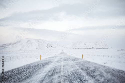 Straight road in snow covered landscape and stormy weather, Route 1, western Iceland © David