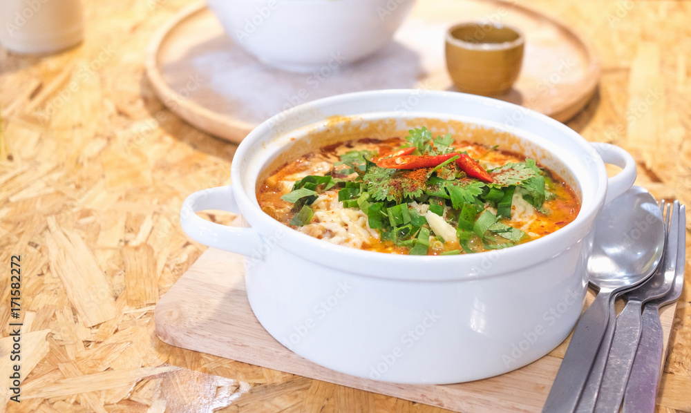 Delicious spicy noodles (Tom Yum) with coriander and vegetables on plywood dining table with copy space Delicious spicy noodles (Tom Yum) with coriander and vegetables on plywood dining table with copy space