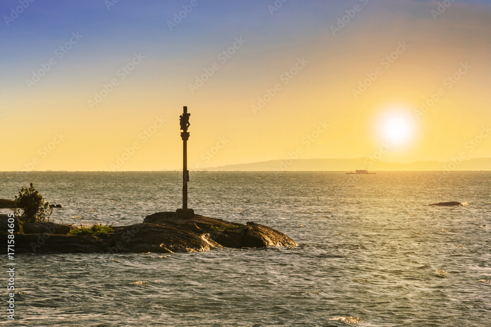 Cross on the sea at sunset