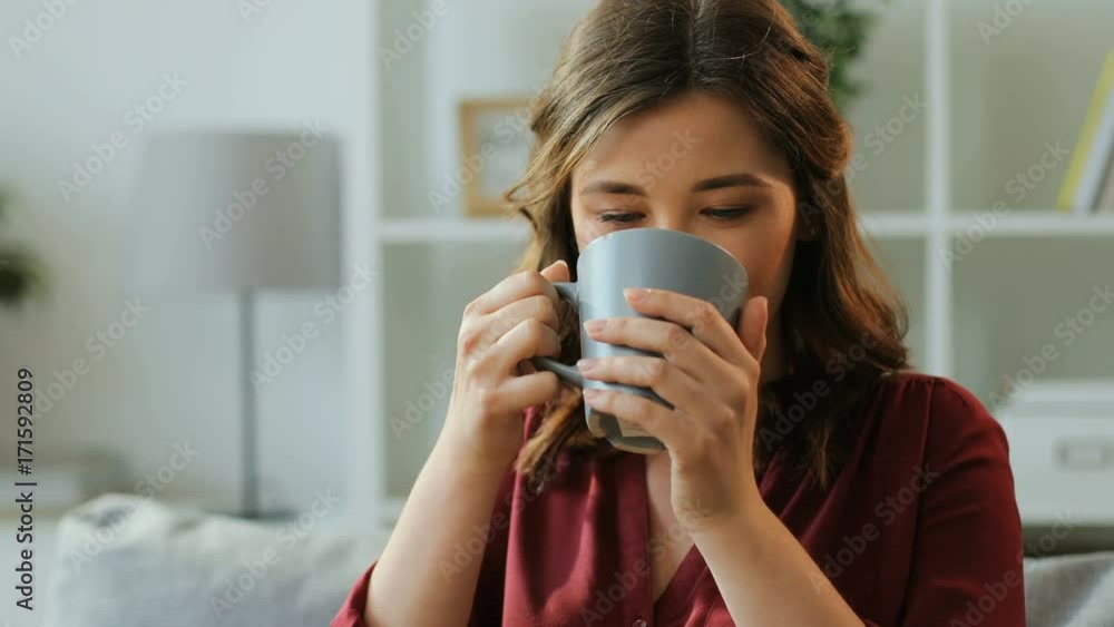 Handsome young woman sitting on the sofe at light living room and drinking coffee, tea. Handsome young woman sitting on the sofe at light living room and drinking coffee, tea.