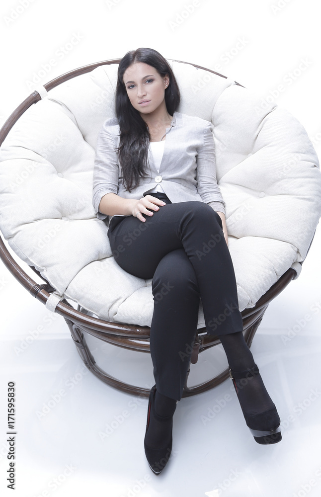 Modern young woman sitting in a round cozy soft chair Modern young woman sitting in a round cozy soft chair