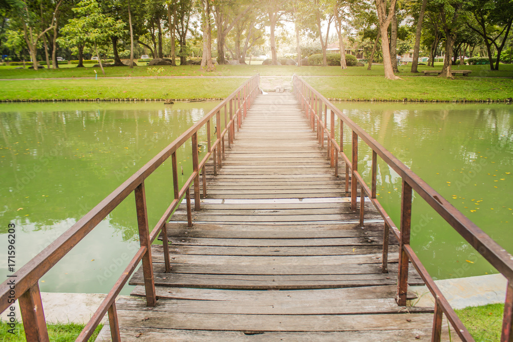 Old wooden bridge with rusted iron rail Take a walk across the river in the middle of nature. Old wooden bridge with rusted iron rail Take a walk across the river in the middle of nature.