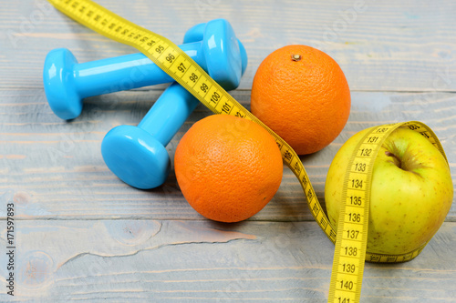 home exercise concept, dumbbells weight with measuring tape and fruit