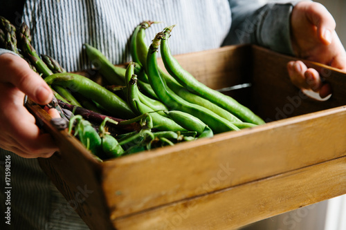 A wooden crate filled with early summer vegetables.