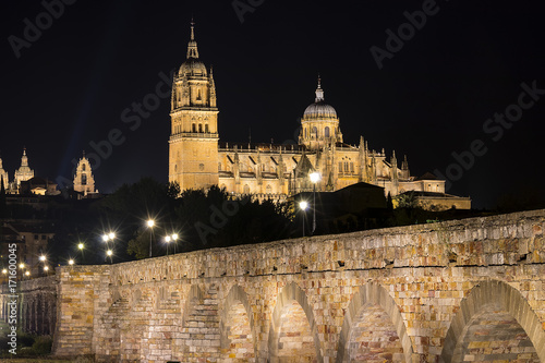 Night view of Salamanca Old and New Cathedrals from roman bridge in Tormes river Community of Castile and Leon, Spain.