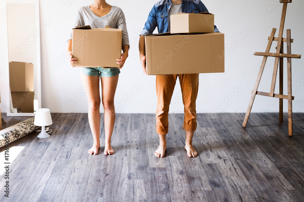 Unrecognizable couple with boxes moving in new house. - obrazy, fototapety, plakaty 