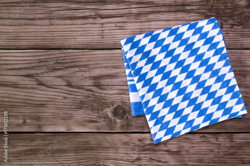 Bavarian white and blue napkin on old wooden table. Oktoberfest background 