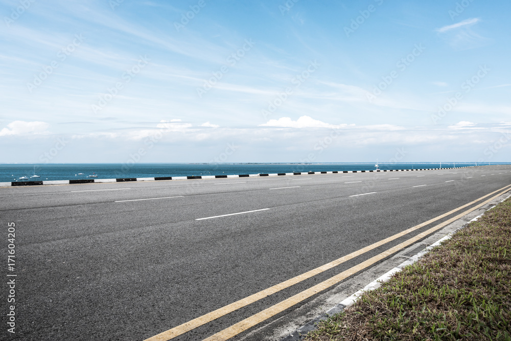 empty asphalt road and blue sea in blue sky