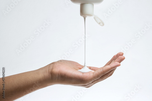 Woman pouring body care lotion from bottle into her hand