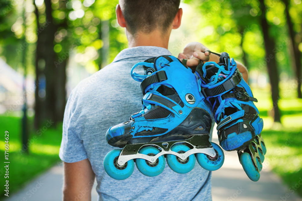 Fototapeta premium Young male roller skater holding inline roller skates.