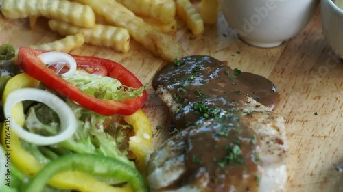 Fish steak with gravy pepper sauce on top with saland and fries side dishes photo