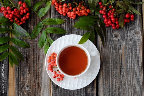 Delicious cup of tea and Rowan berries on a wooden table