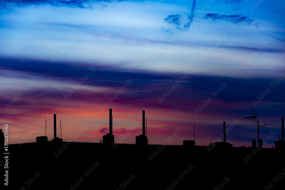 Landscape with silhouette of buildings under colorful sunset sky.