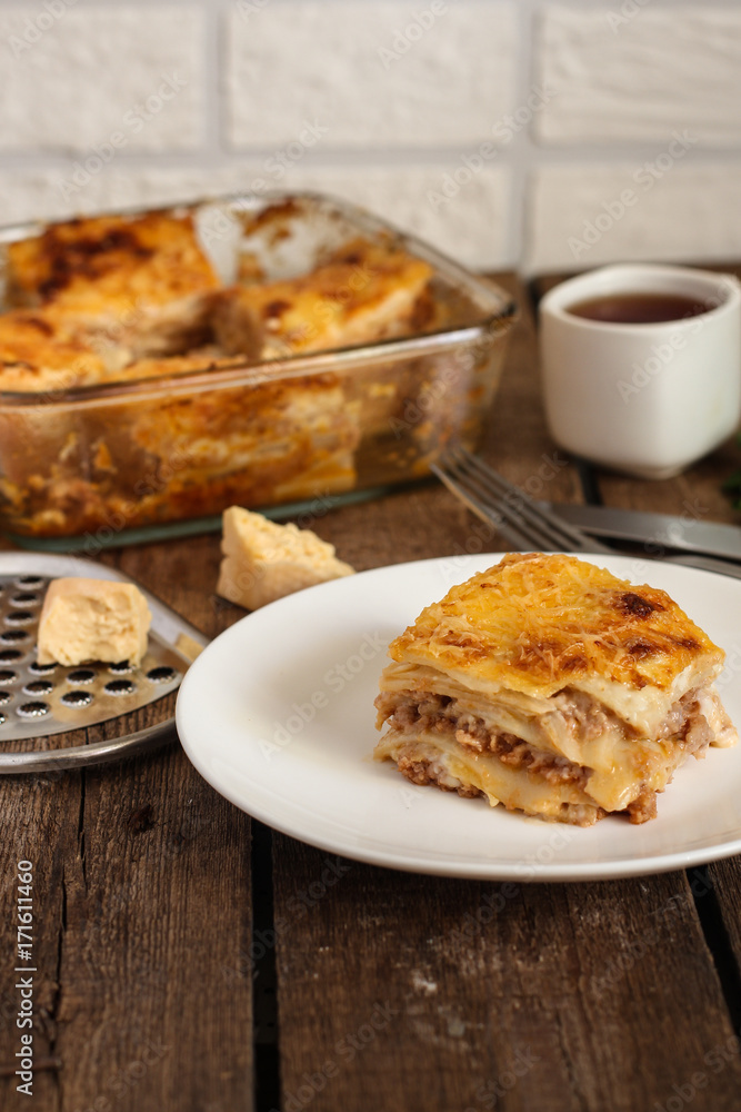 piece of lasagna in a white plate on a wooden surface