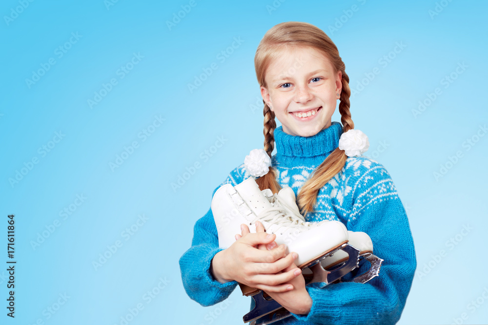 Cheerful little girl in blue warm sweater holding figure skates. White background. Cheerful little girl in blue warm sweater holding figure skates. White background.