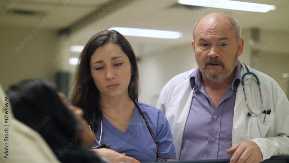 A nurse and doctor deliver bad news to a patient in a hospital bed. A nurse and doctor deliver bad news to a patient in a hospital bed.