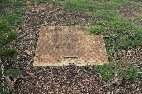 Locked worn metal trapdoor outdoors in grass