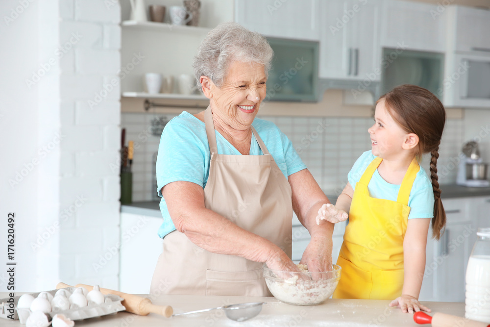 Cute little girl and her grandmother cooking on kitchen Cute little girl and her grandmother cooking on kitchen