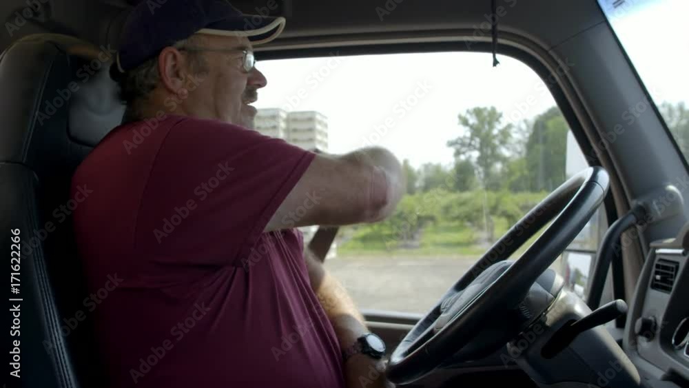 Truck driver puts on seat belt while behind the wheel in daylight interior, summer day. Hand-held slow motion 4K recorded at 60fps. Truck driver puts on seat belt while behind the wheel in daylight interior, summer day. Hand-held slow motion 4K recorded at 60fps.