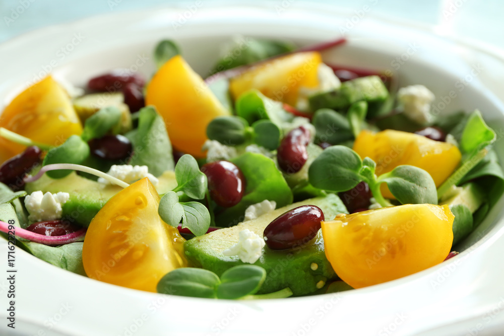 Superfood salad with yellow tomato, beans and zucchini in white ceramic plate, closeup