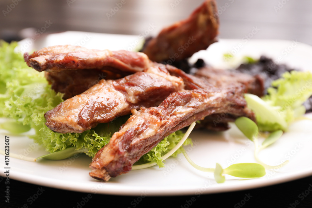 Delicious ribs served with salad on plate, closeup