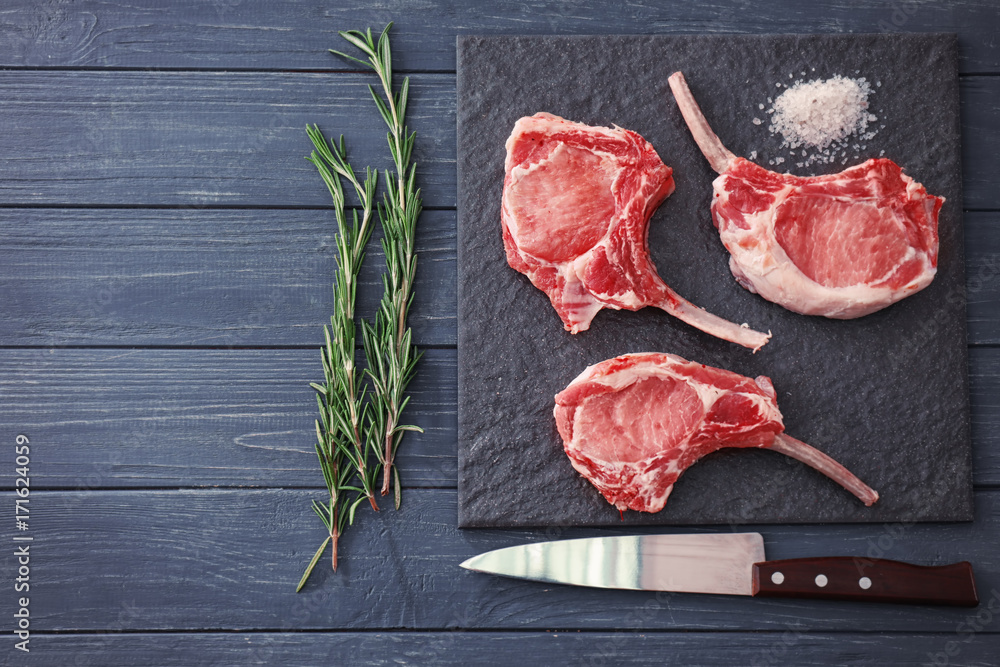 Composition with raw ribs, knife and rosemary on wooden background