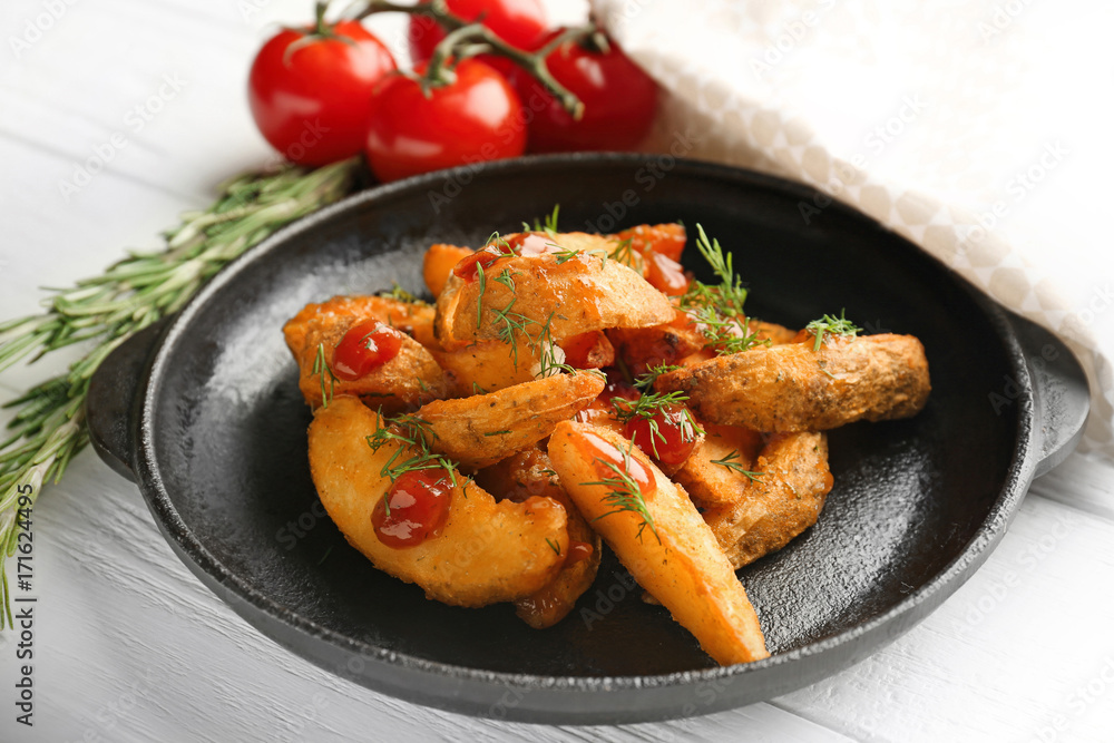 Frying pan with delicious baked potato wedges on table Frying pan with delicious baked potato wedges on table