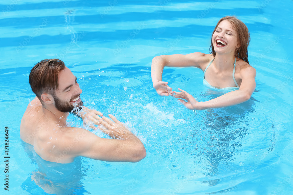Happy young couple playing in swimming pool