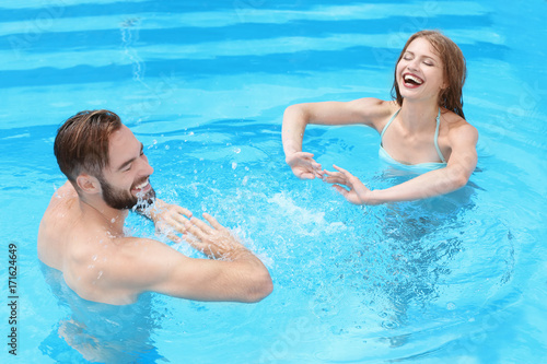 Happy young couple playing in swimming pool © Africa Studio