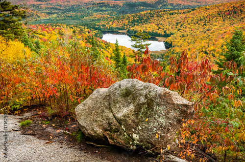 Rock and small lake in a forest of pines, birches and maples in autumn in Quebec