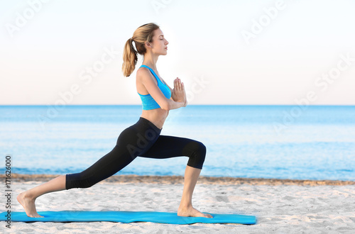 Beautiful young woman practicing yoga on sea beach © Africa Studio