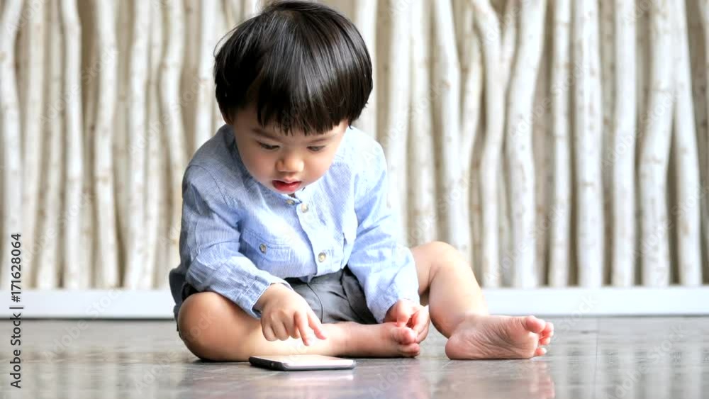 Little boy watching on cellphone and sitting on the floor Little boy watching on cellphone and sitting on the floor