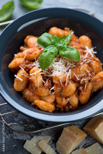 Close-up of potato gnocchi with meat sauce topped with parmesan, selective focus