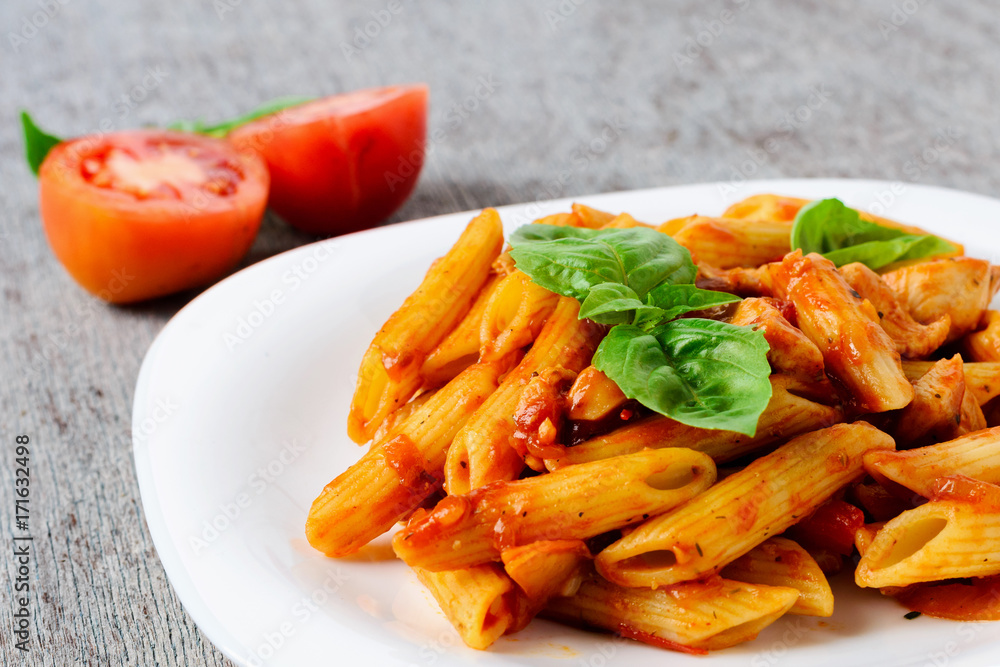 Penne with tomato sauce and basil on wooden background Penne with tomato sauce and basil on wooden background