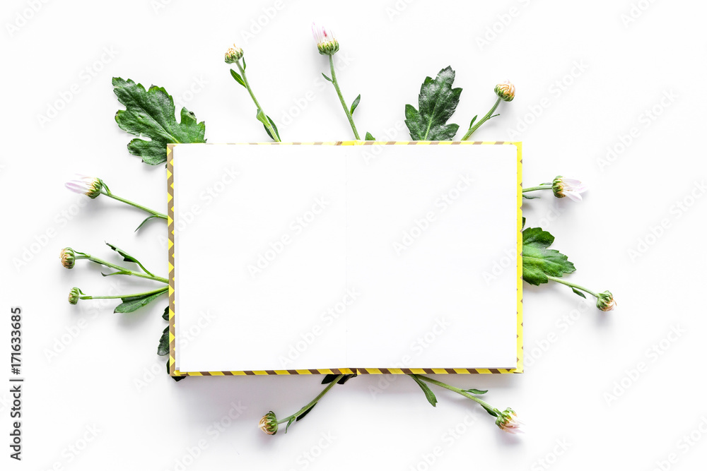Floral mockup. Notebook among buds and leaves on white background top view