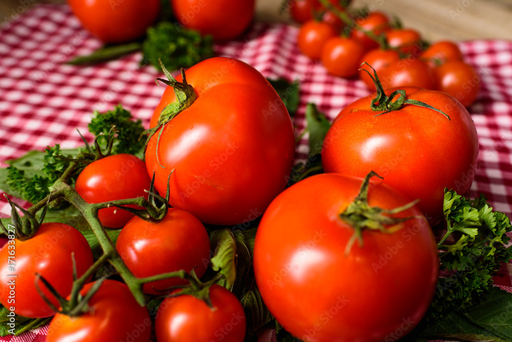 Many tomatoes are placed on a plaid tablecloth. Many tomatoes are placed on a plaid tablecloth.